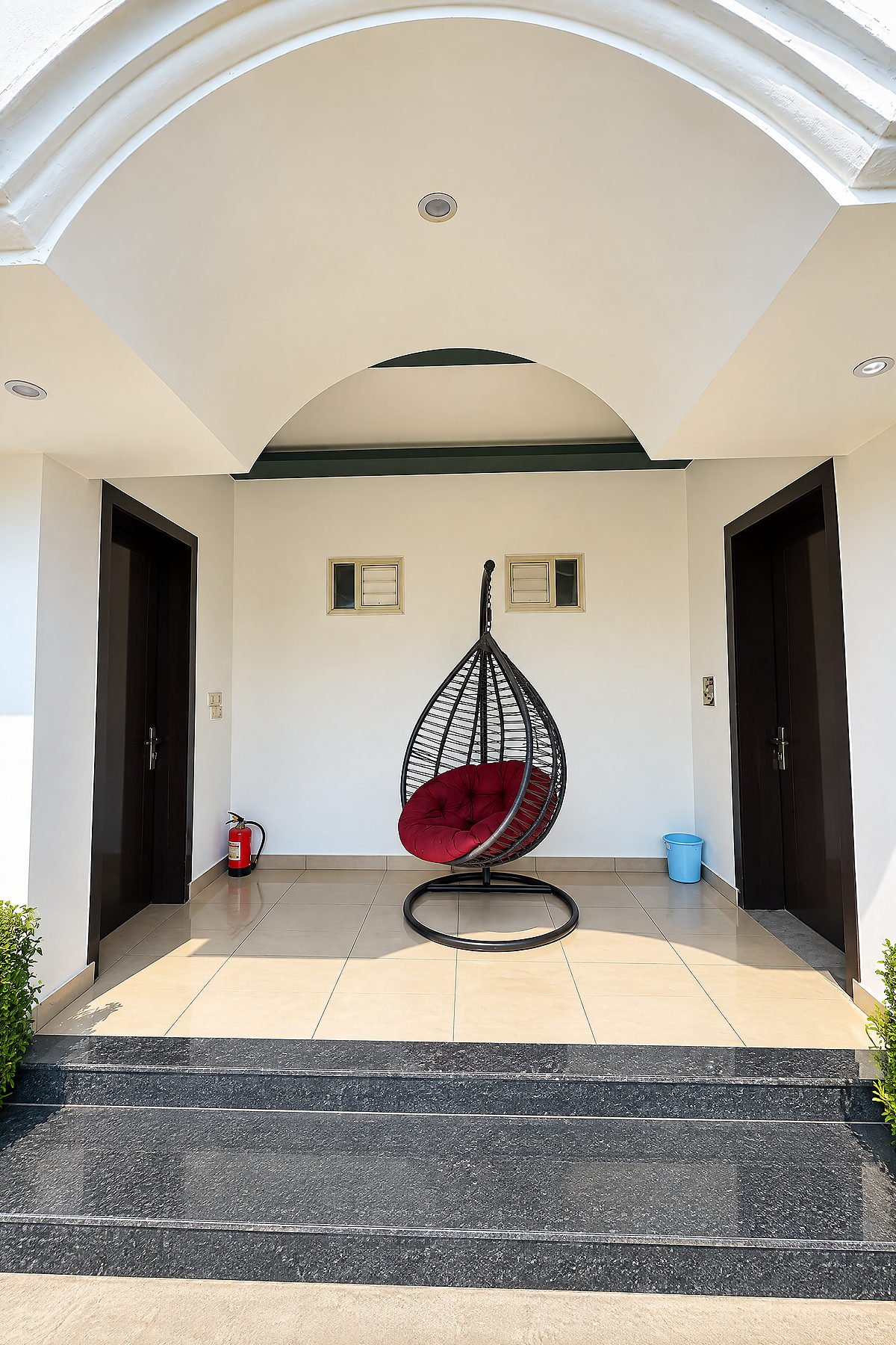 Arched entrance porch with a woven hanging chair at The White House Pilibhit