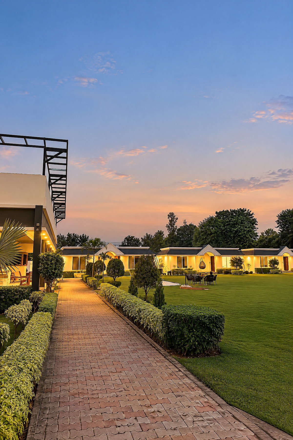 Paved garden pathway leading to the guest cottages at The White House Pilibhit in the evening