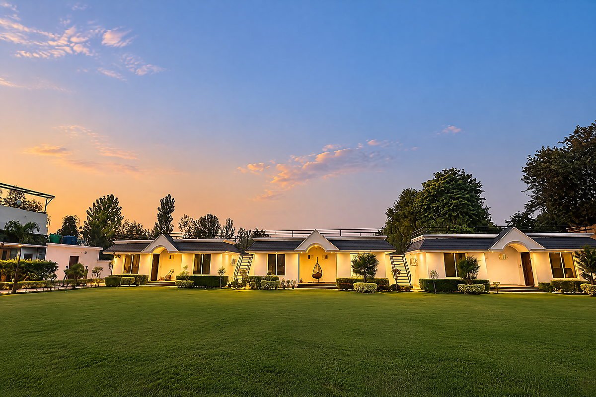 A row of illuminated cottages along the lawn at The White House Pilibhit