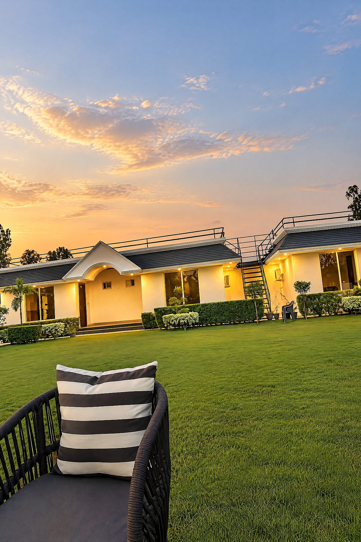 Cushioned lawn chairs beside the garden in the evening at The White House Pilibhit