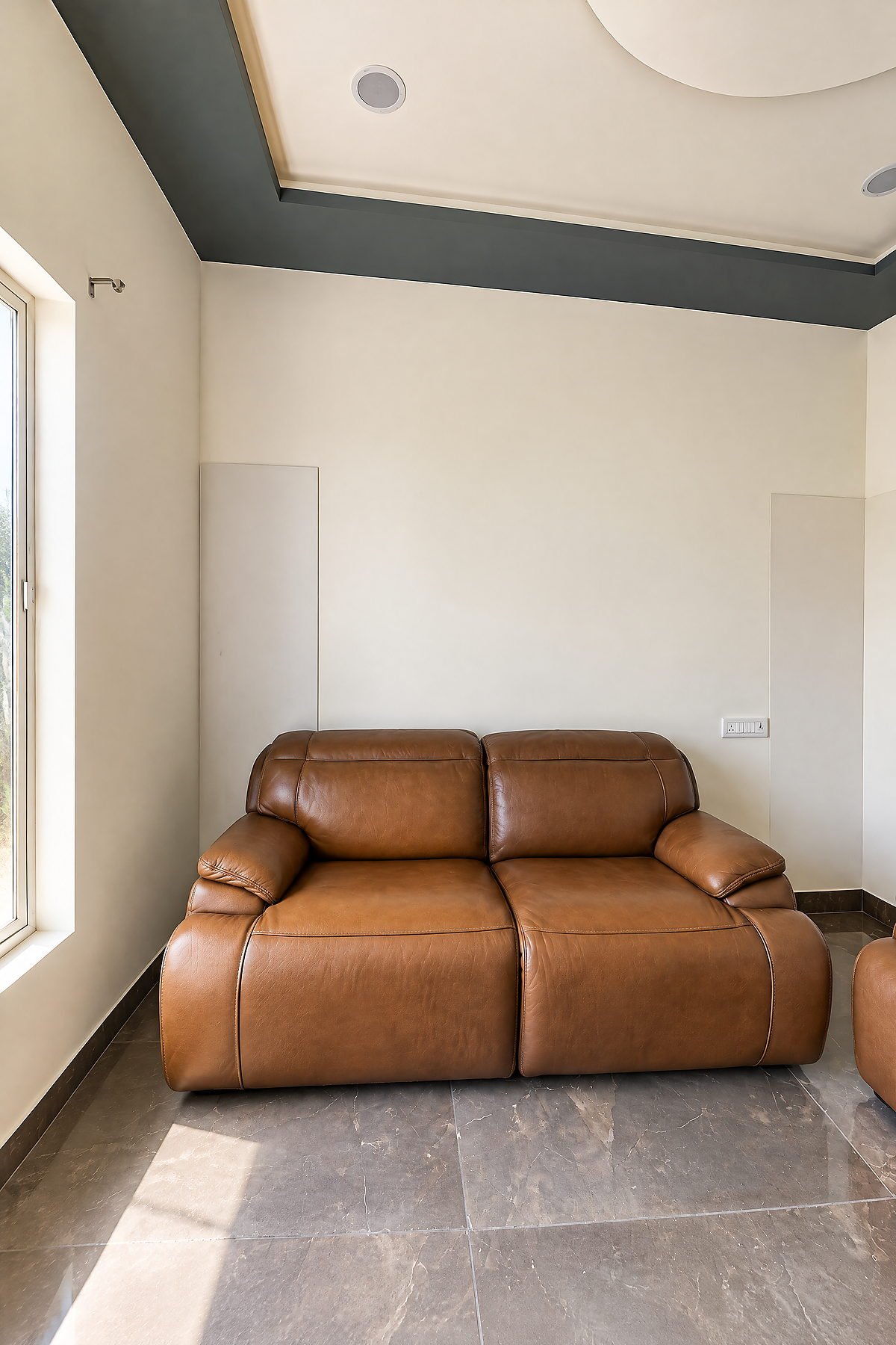 Leather recliner beside a bright window in the lounge at The White House Pilibhit