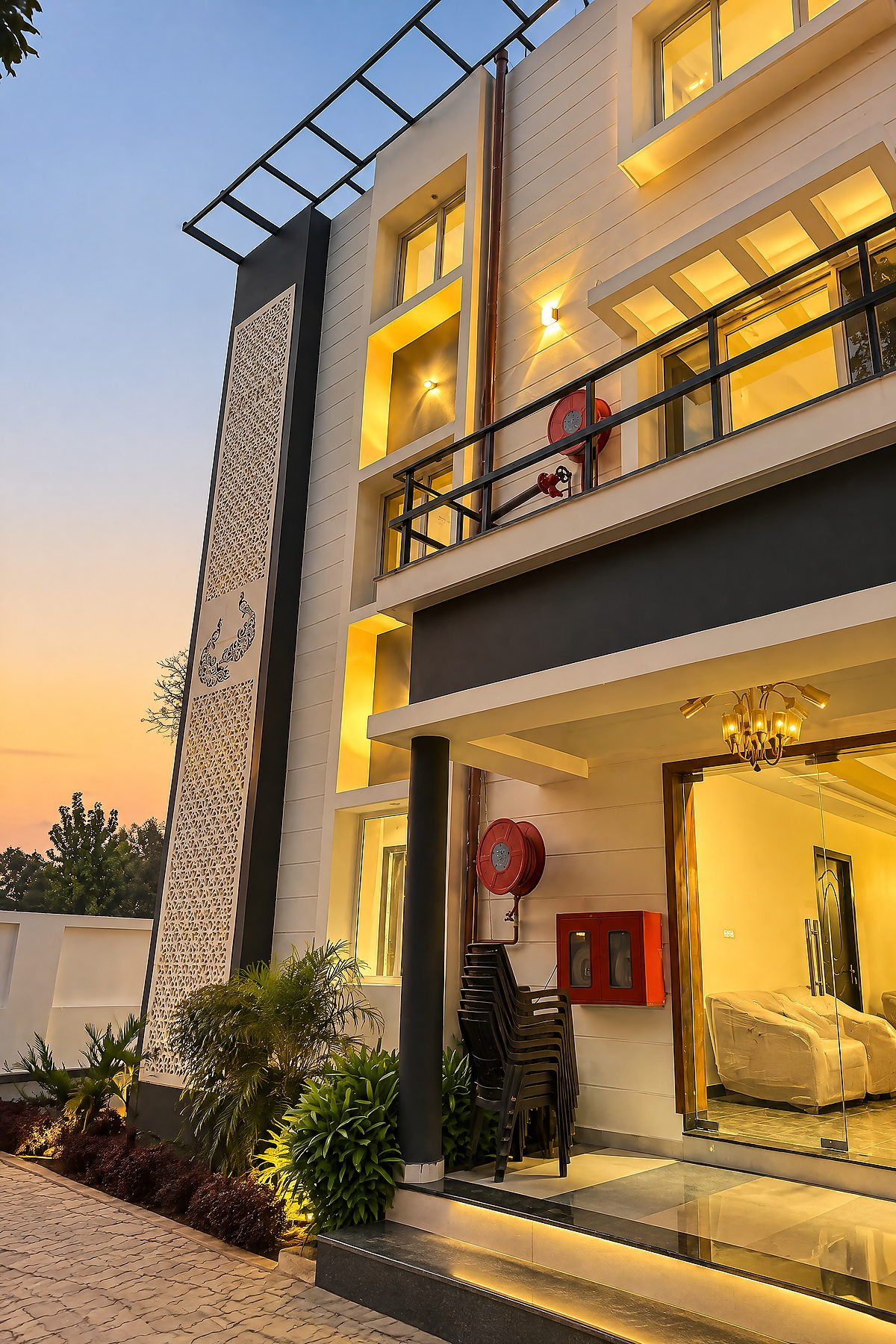 The multi-level block of The White House Pilibhit lit from within at dusk
