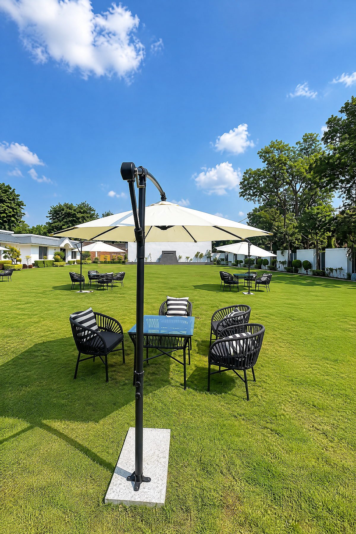 Outdoor dining tables under white parasols on the lawn at The White House Pilibhit
